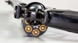 A loaded .357 Magnum revolver sitting on a table with the cylinder partly out. | Juan Llauro | Dreamstime.com