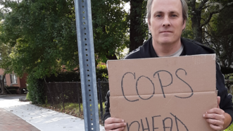 Michael Friend standing on the sidewalk holding a sign that reads 'cops ahead' | ACLU of Connecticut