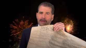 John Stossel holding up a copy of the US Constitution | Stossel TV